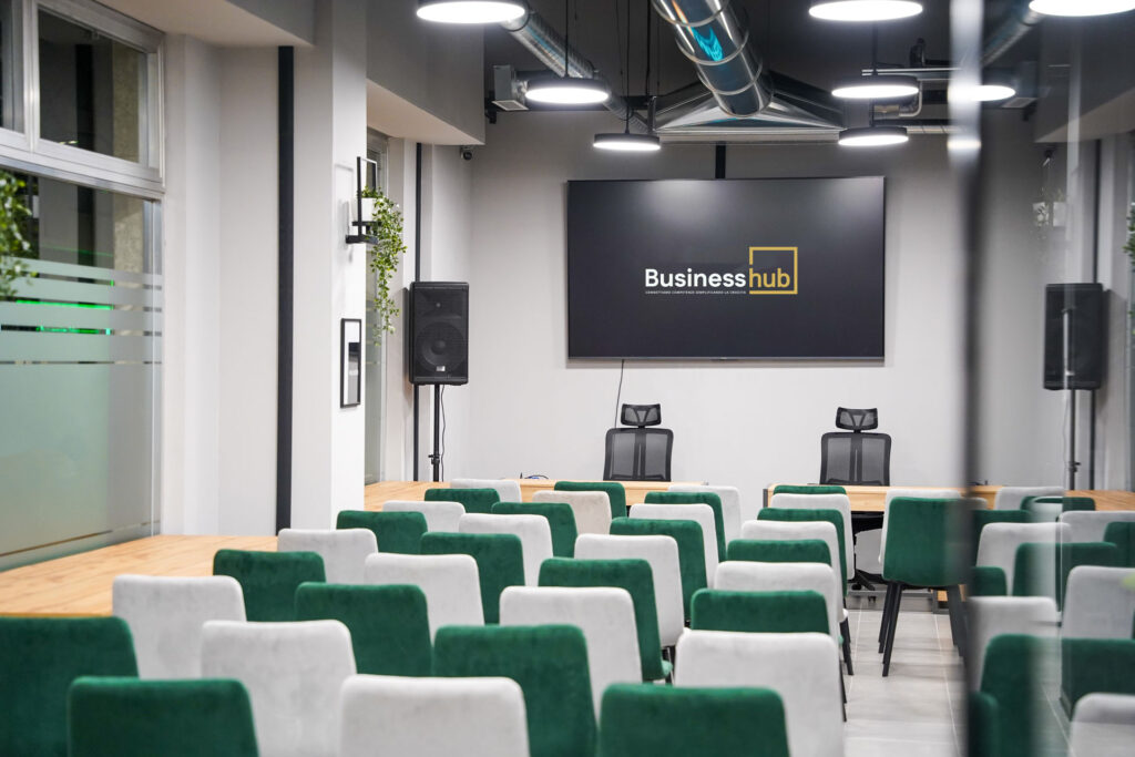 Sala riunioni e formazione di Business Hub con schermo di presentazione e sedute in velluto